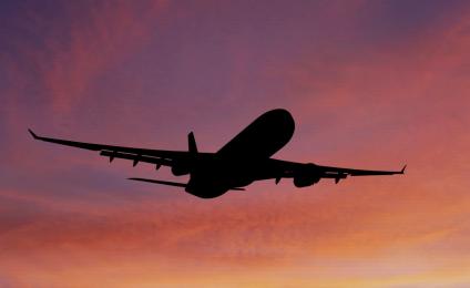 Silhouette of an airplane flying in the sunset